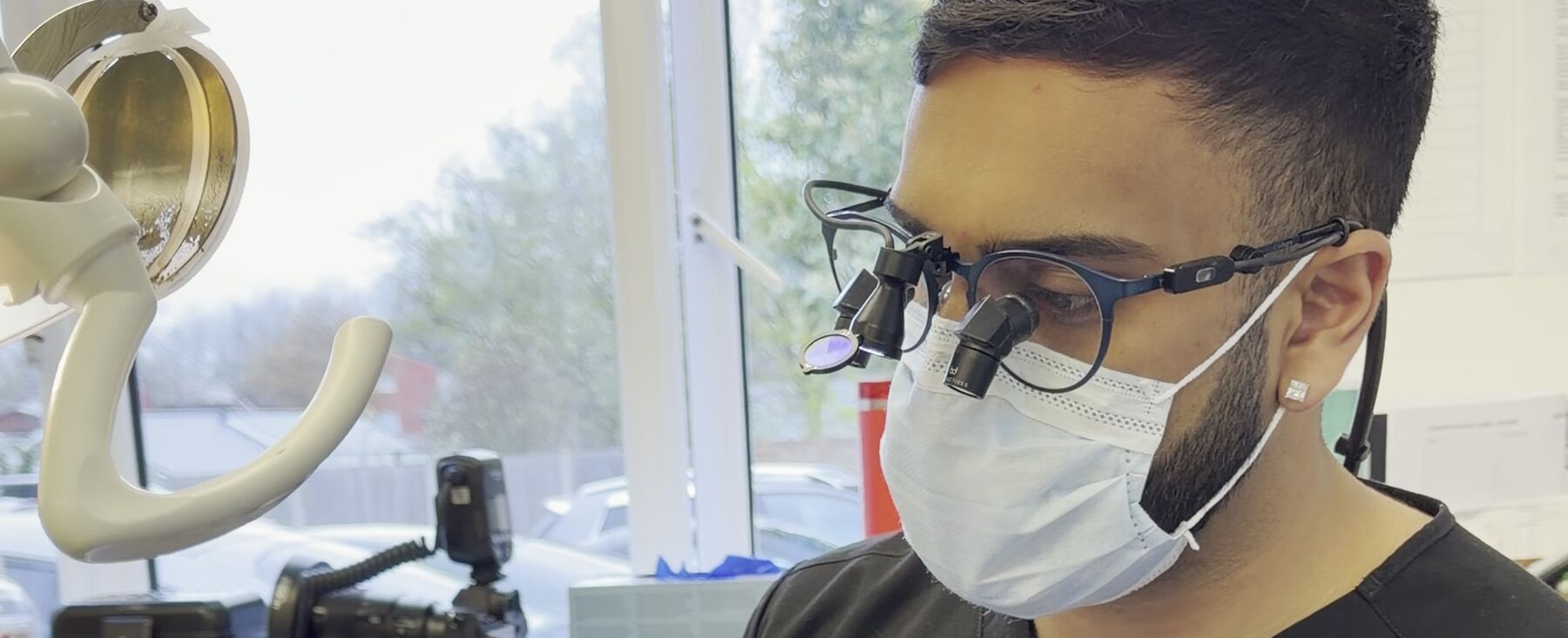 Cameron at work in loupes and a mask at the practice
