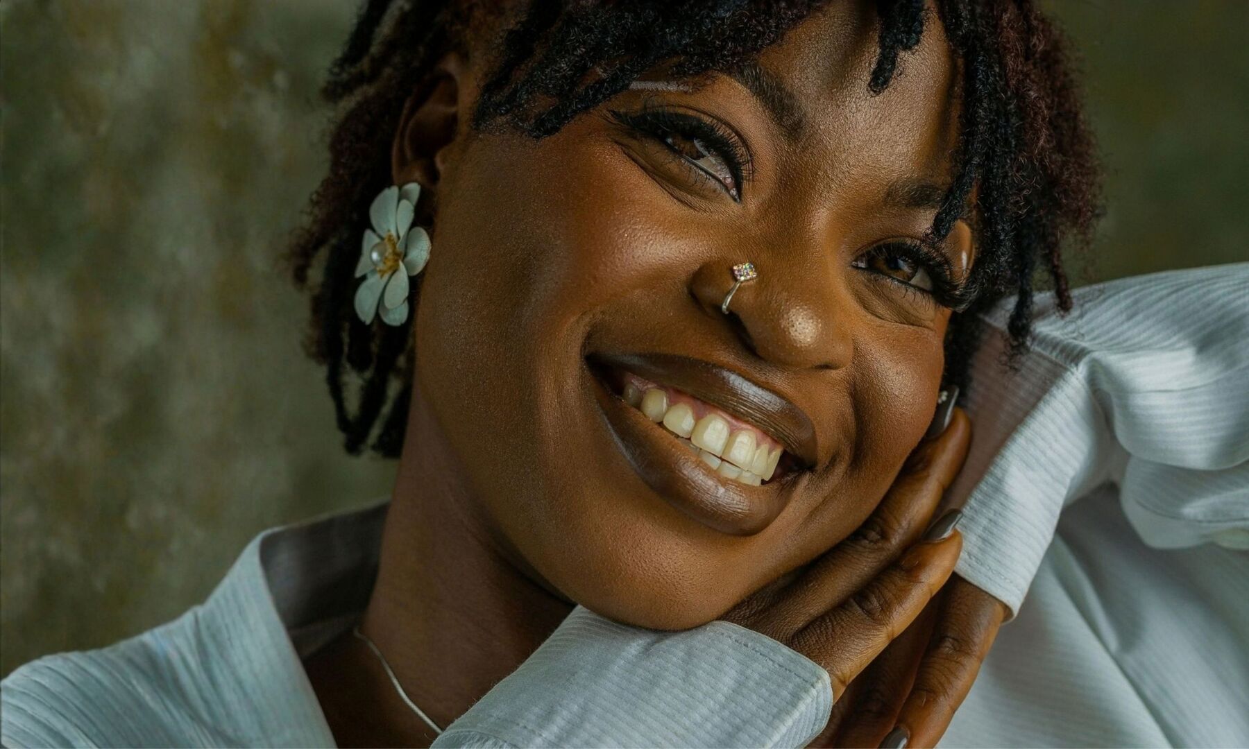A woman smiling with her hand against her cheek
