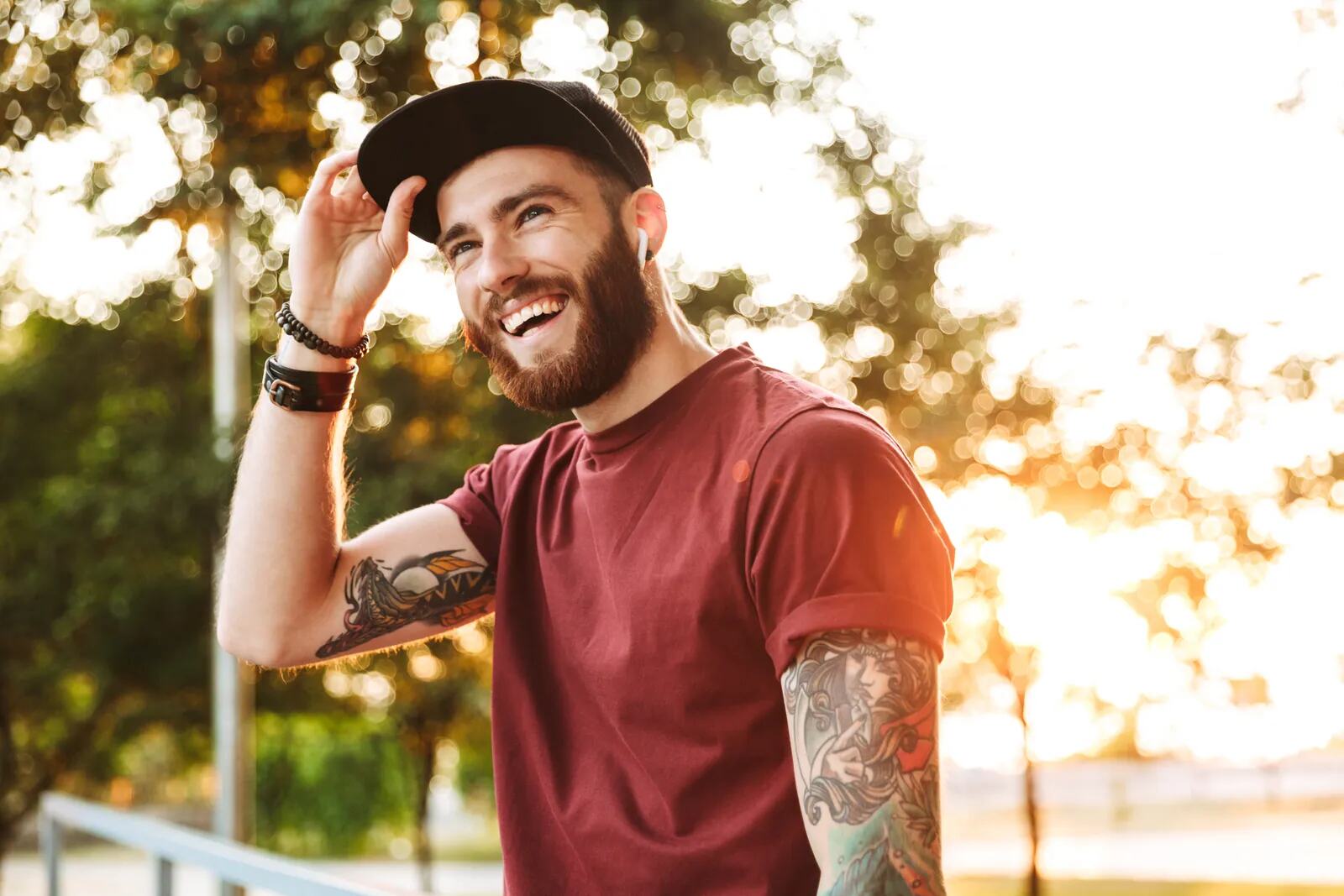 A bearded man laughing outdoors in the evening sun