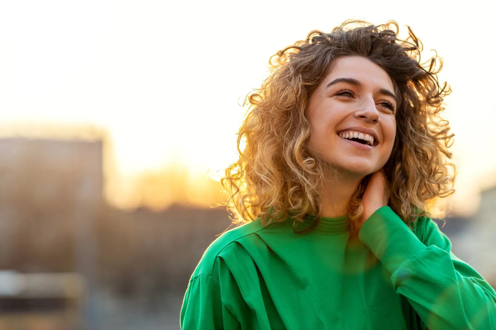 A woman with curly hair smiling in the sunshine