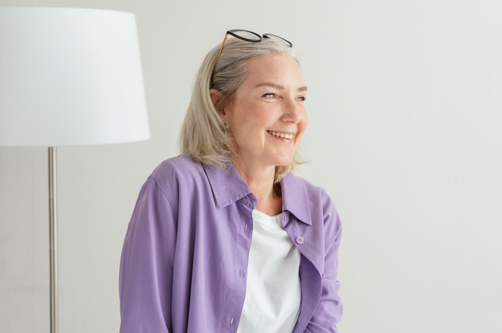 A woman with grey hair smiling, looking to one side