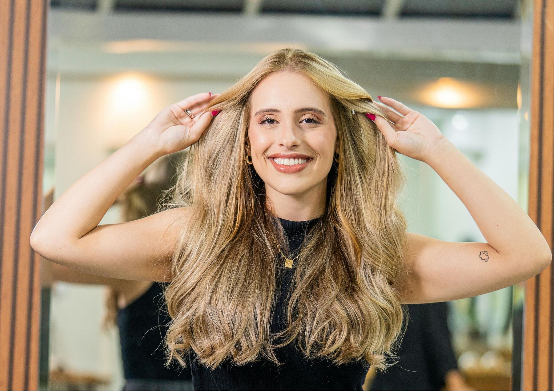 A young woman smiling with her hands in her hair