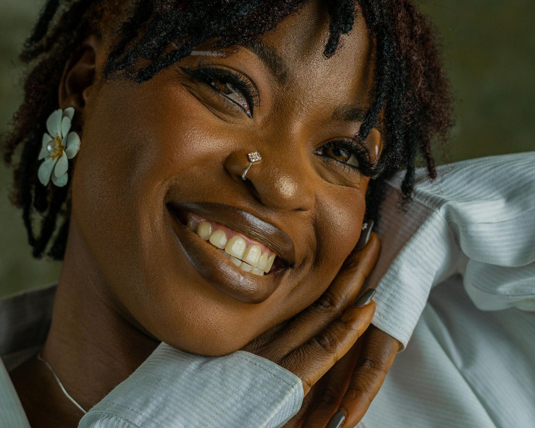 A woman smiling openly, her head resting on her hand